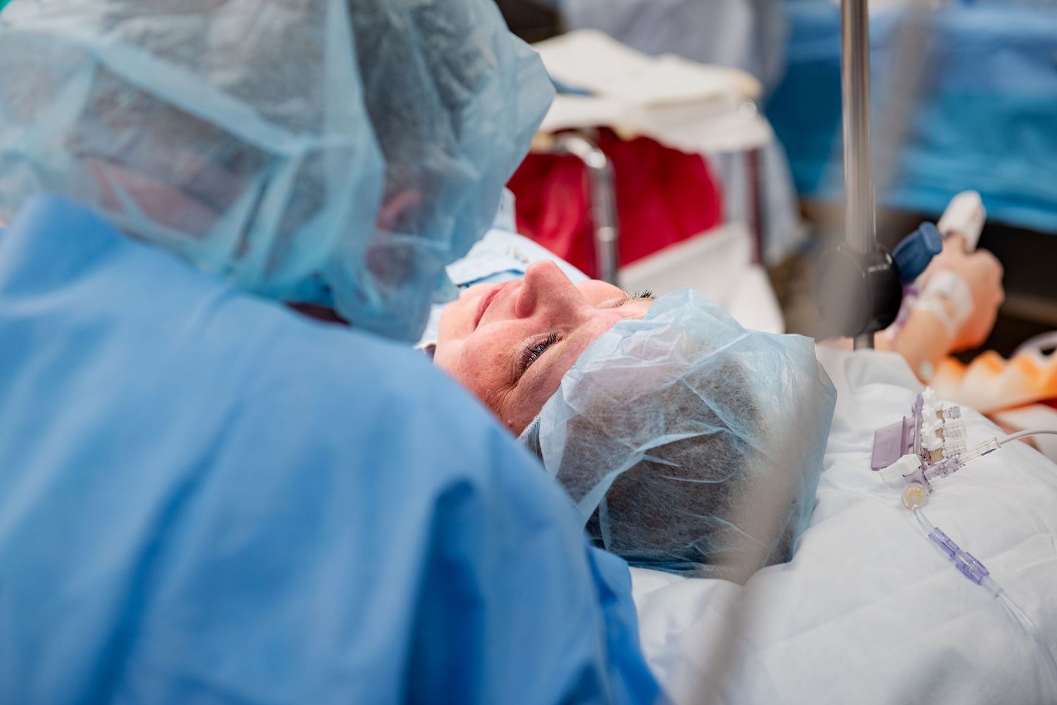 Medical professionals in blue scrubs and protective gear perform surgery in an operating room setting.