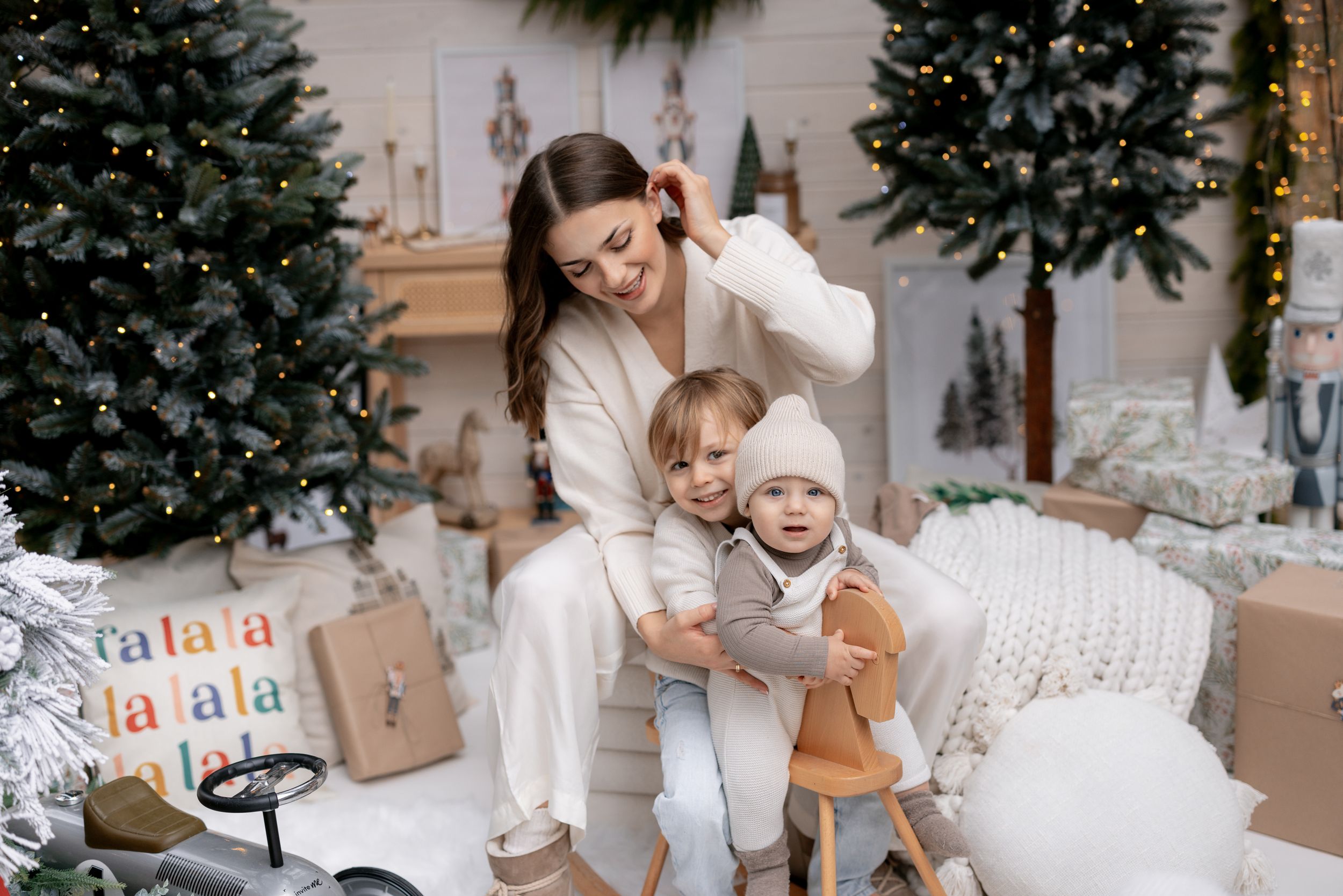 Joyful moment between family members in white clothing surrounded by Christmas decorations.