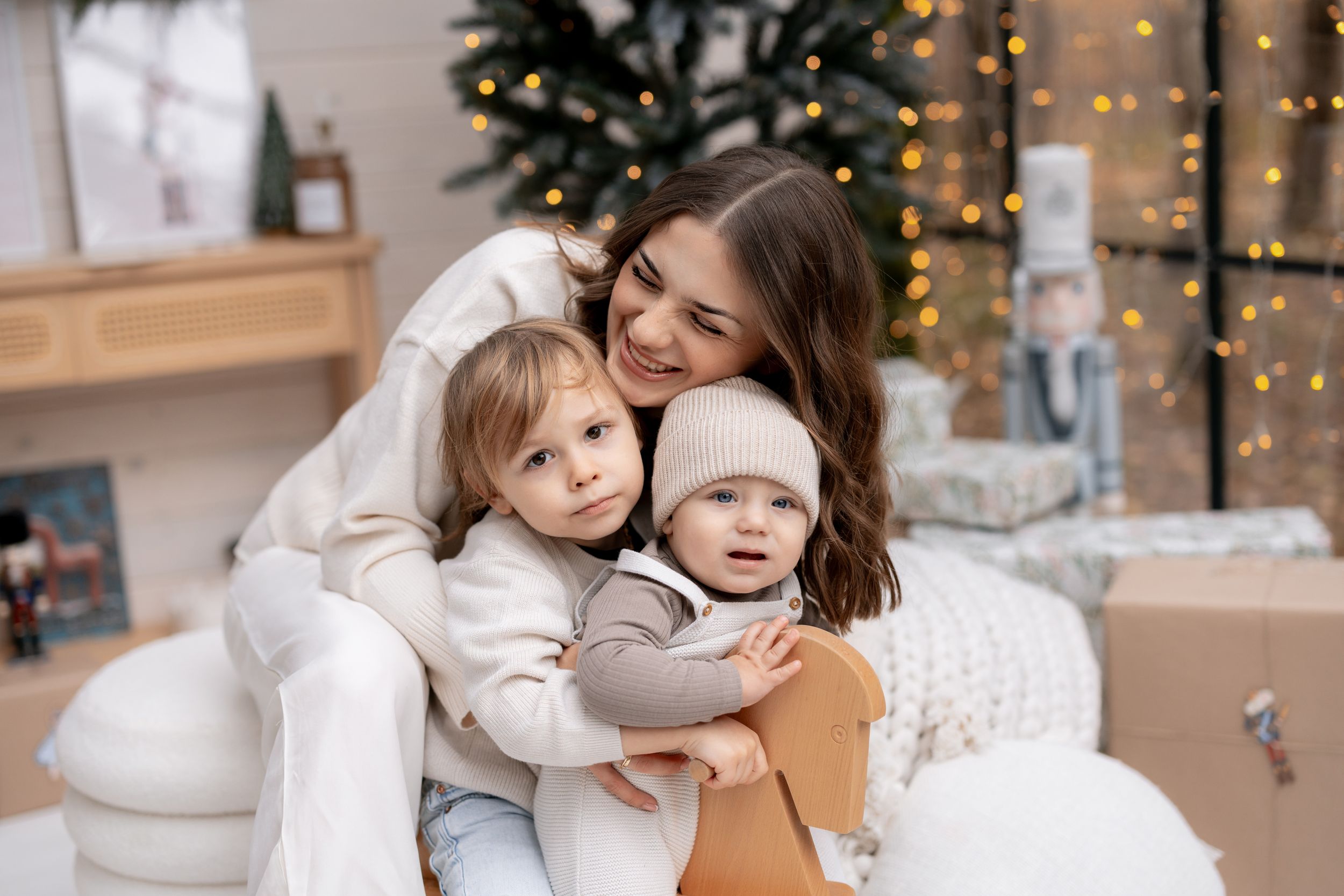 Warm family embrace during holiday photoshoot with Christmas trees and decor in background.