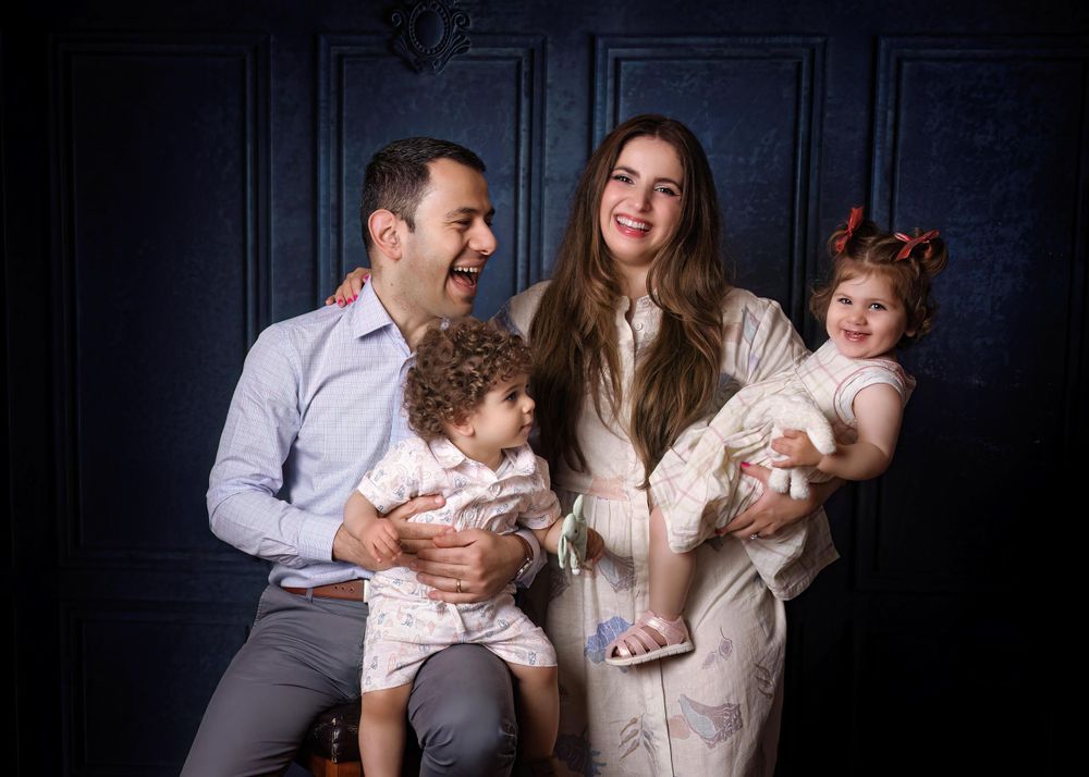 Family portrait of mother, father and two children family is laughing while mother is looking at the camera.