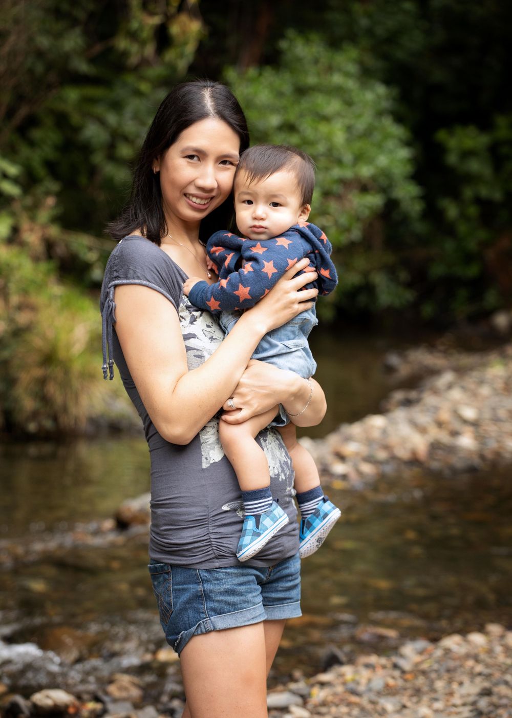 Portrait of mother and son outside with river in the background.