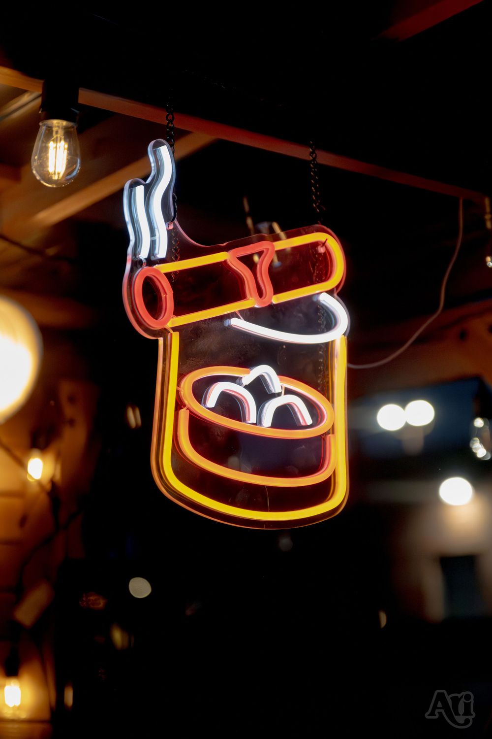 Neon sign displaying a smoking whiskey glass with glowing lights in the background.