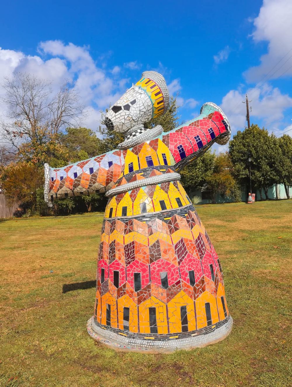 Colorful outdoor art installation featuring curved metal structures in yellow and orange hues on grassy field.