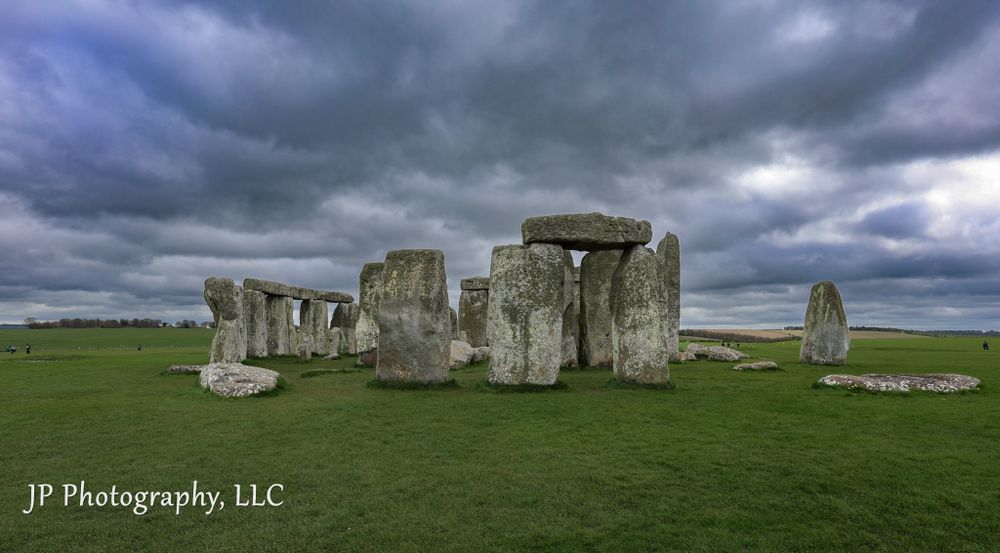 Ancient Stonehenge monument under dramatic stormy sky in English countryside.