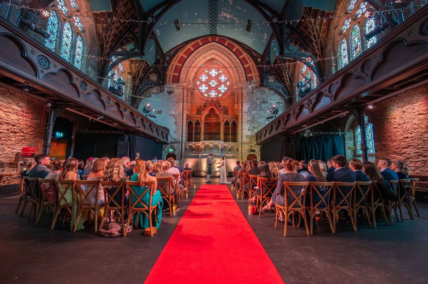 Gothic church interior decorated for an event with red carpet and ambient lighting creating a dramatic atmosphere.