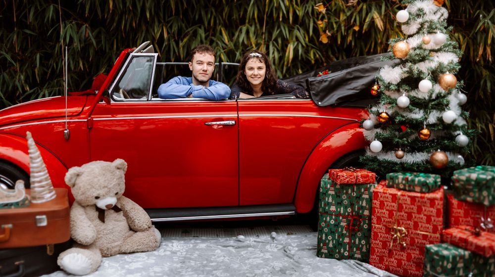Mini-session photo de Noël 2024 avec une coccinelle VW rouge décorée pour les fêtes, créant une ambiance festive et chaleureuse.