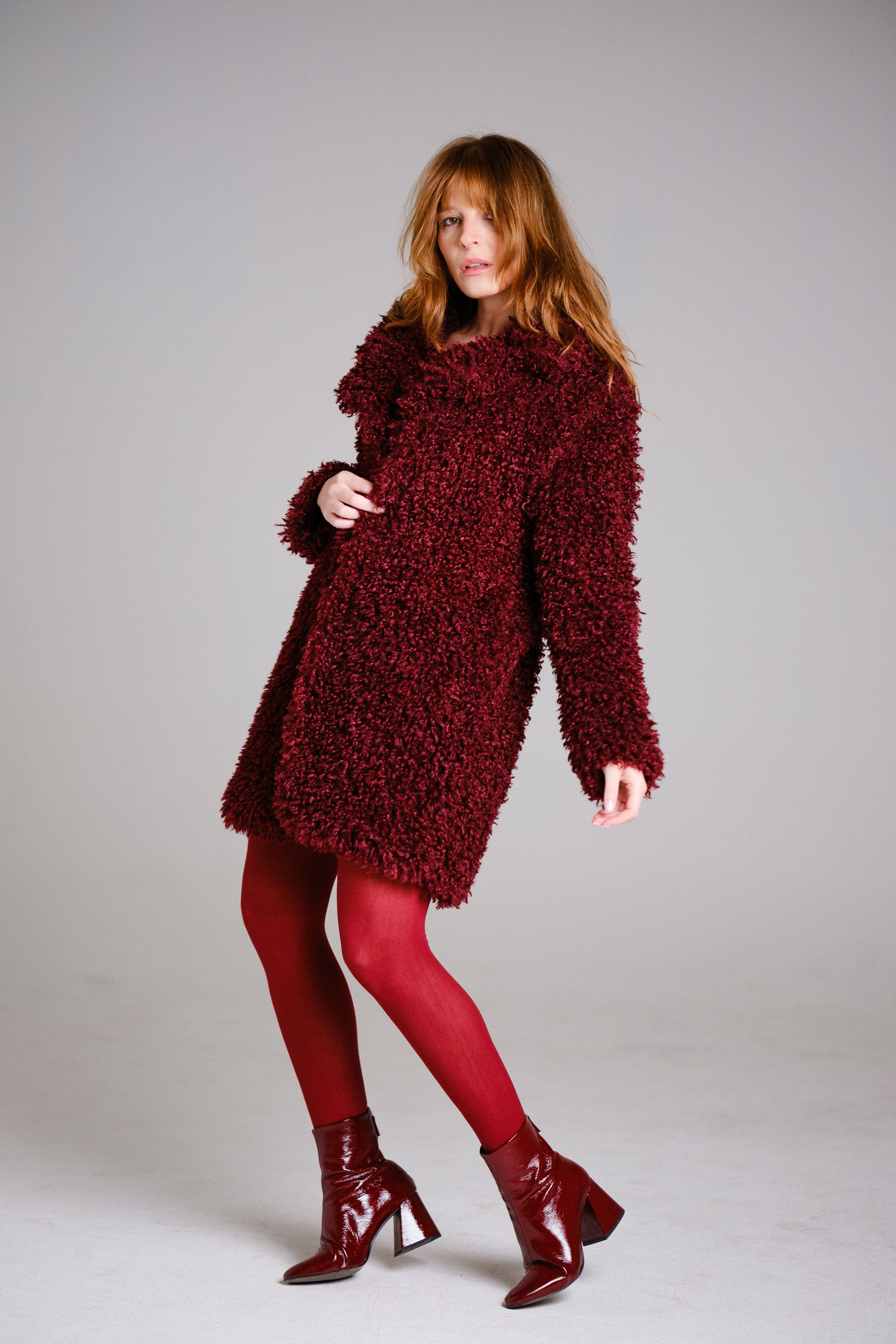 Fashion shoot featuring all-burgundy outfit with textured coat and matching boots.