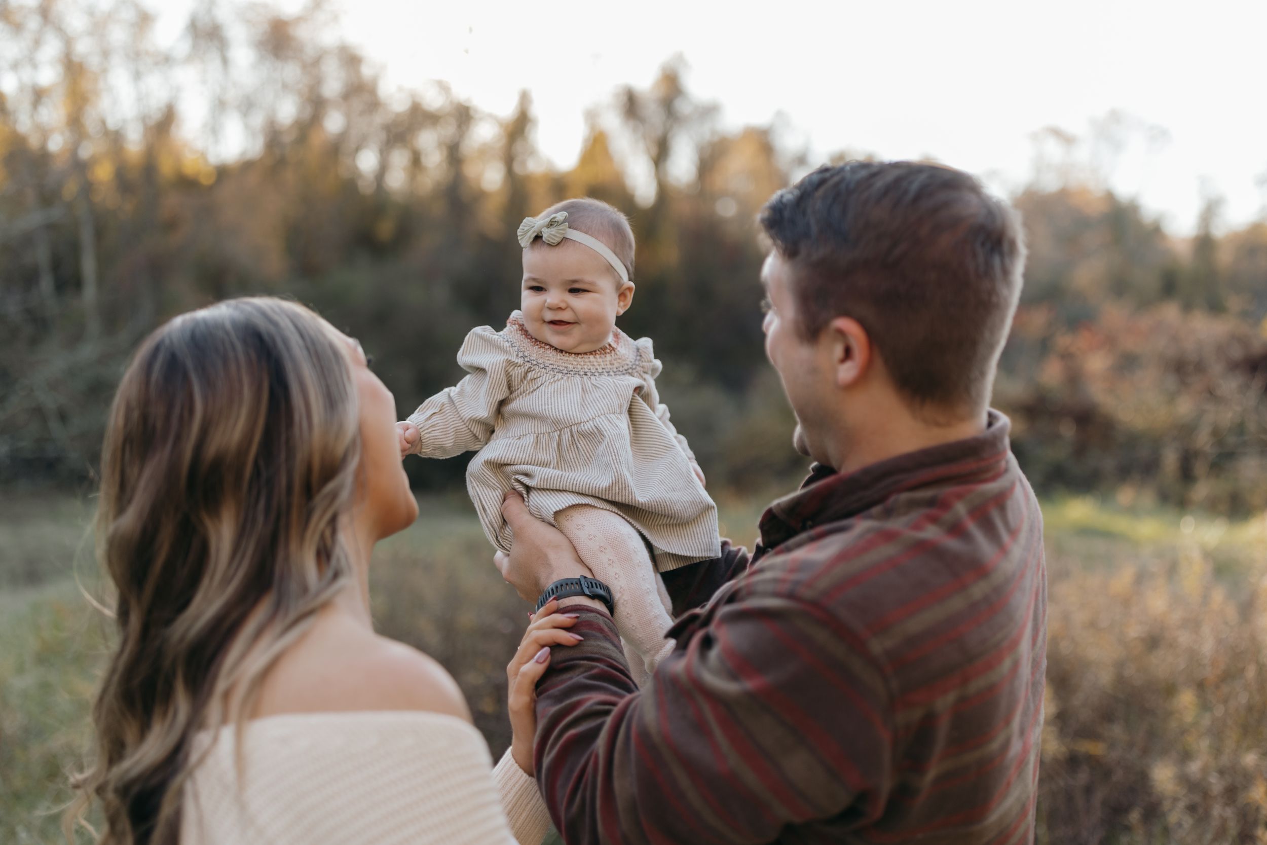 Family portrait at sunset with baby in warm autumn tones.