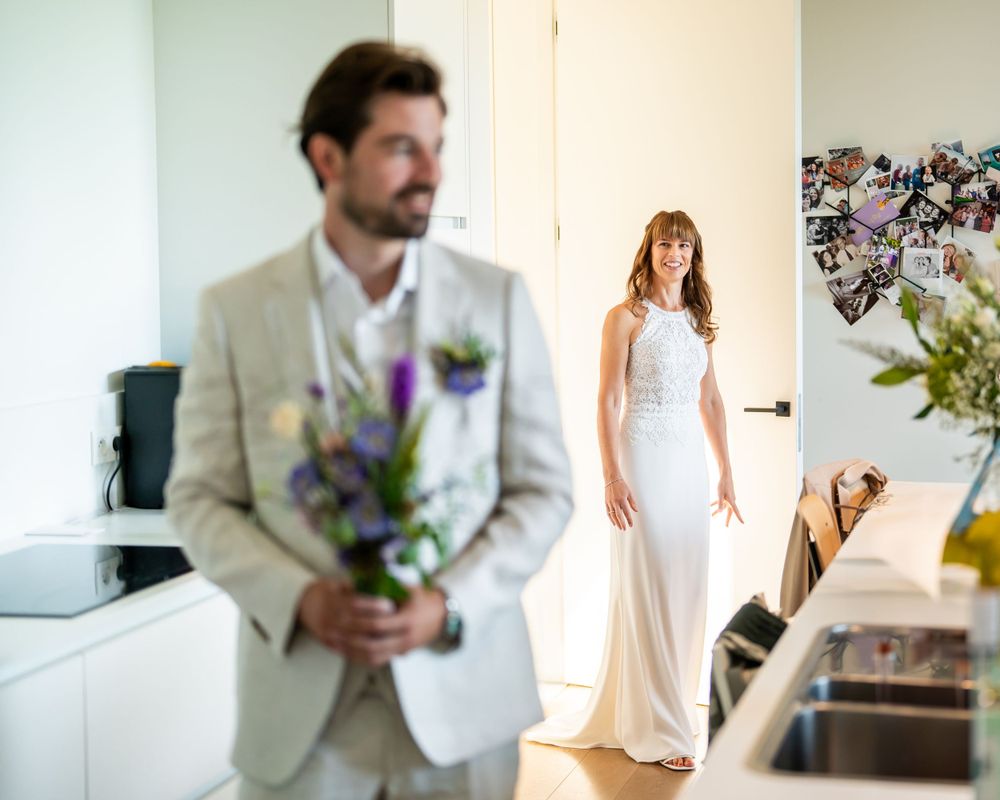 A split photo showing a groom holding purple flowers and a bride in an elegant white fitted wedding gown.