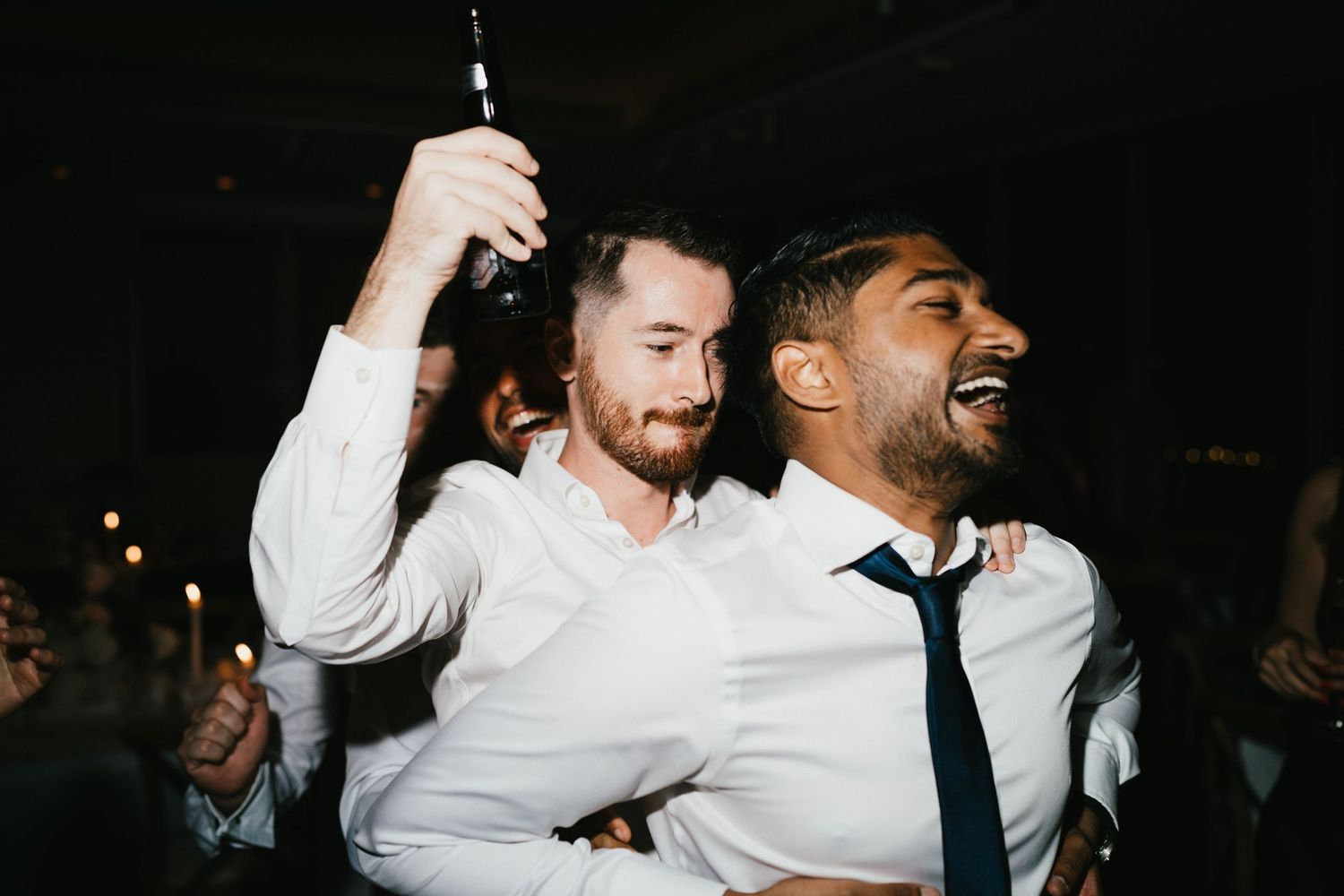 Two guests in white shirts and ties celebrate together at a nighttime party.