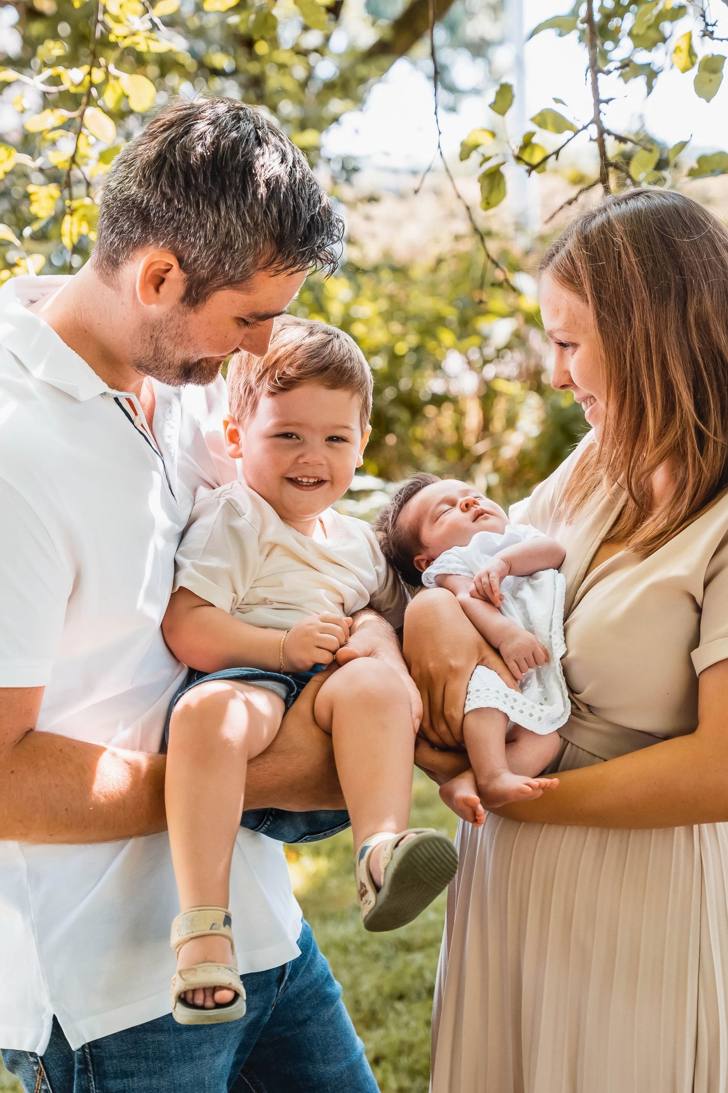 Happy family of four sharing loving moment together under tree branches.