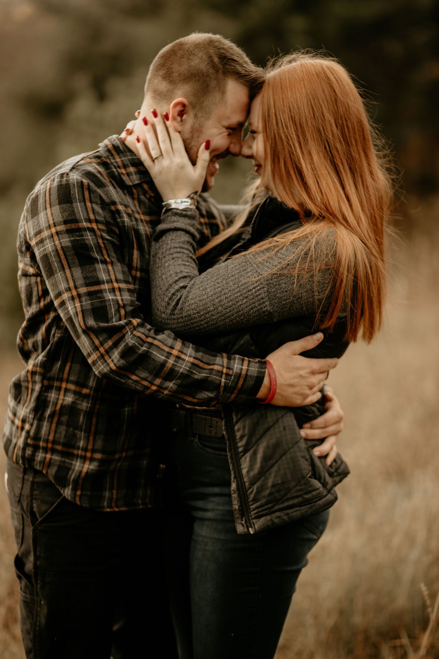 Intimate couple embracing in plaid shirt and sweater during autumn outdoor photoshoot.