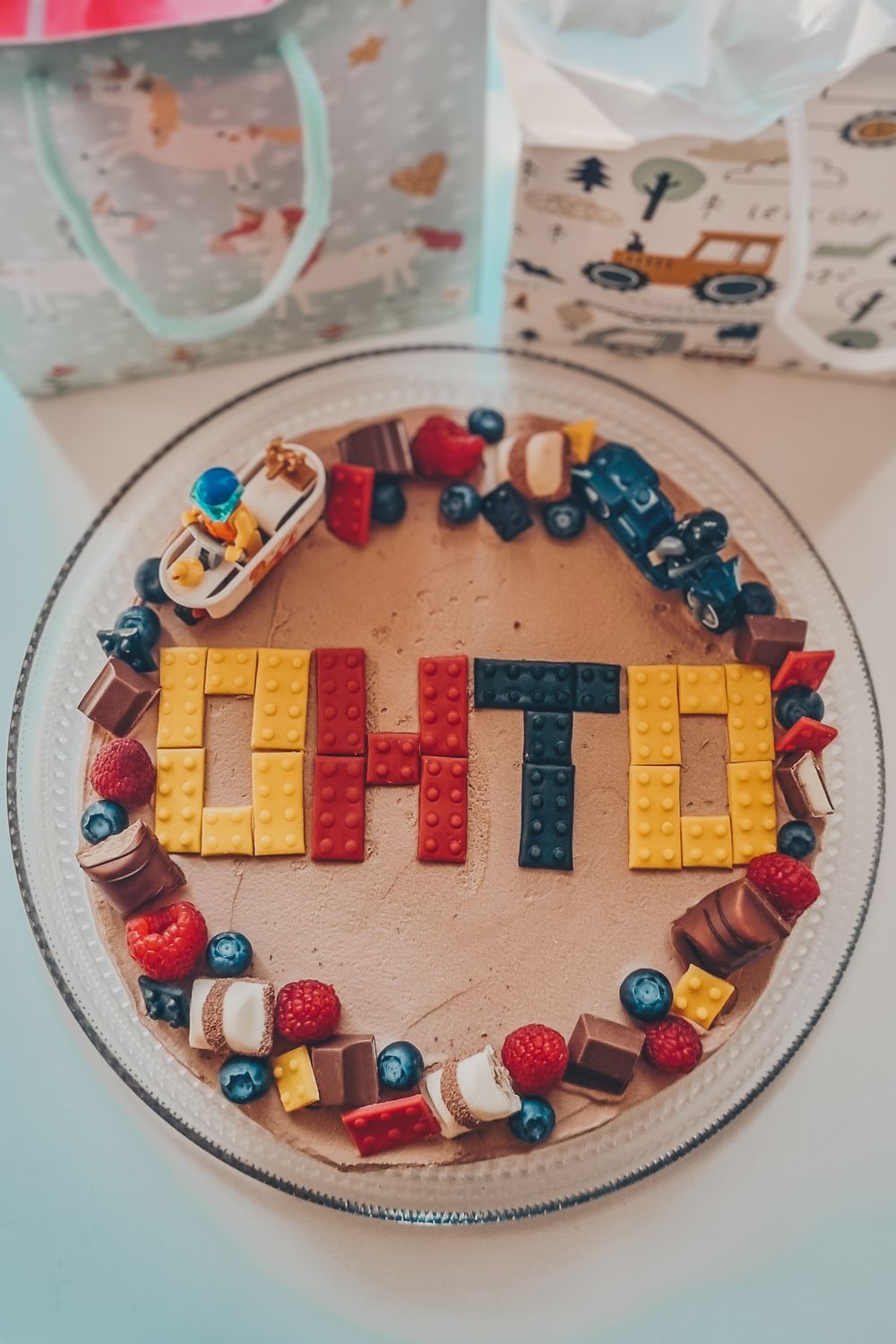 A round cake decorated with toy trains and colorful letter blocks spelling 'OTTO'.