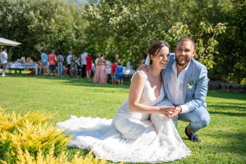 Wedding couple poses playfully on grass with natural garden backdrop.