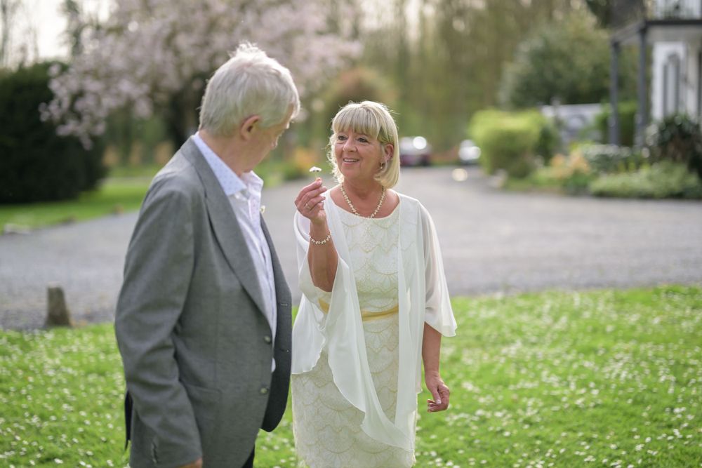 Elegant wedding couple embraces outdoors on a spring day surrounded by cherry blossoms.