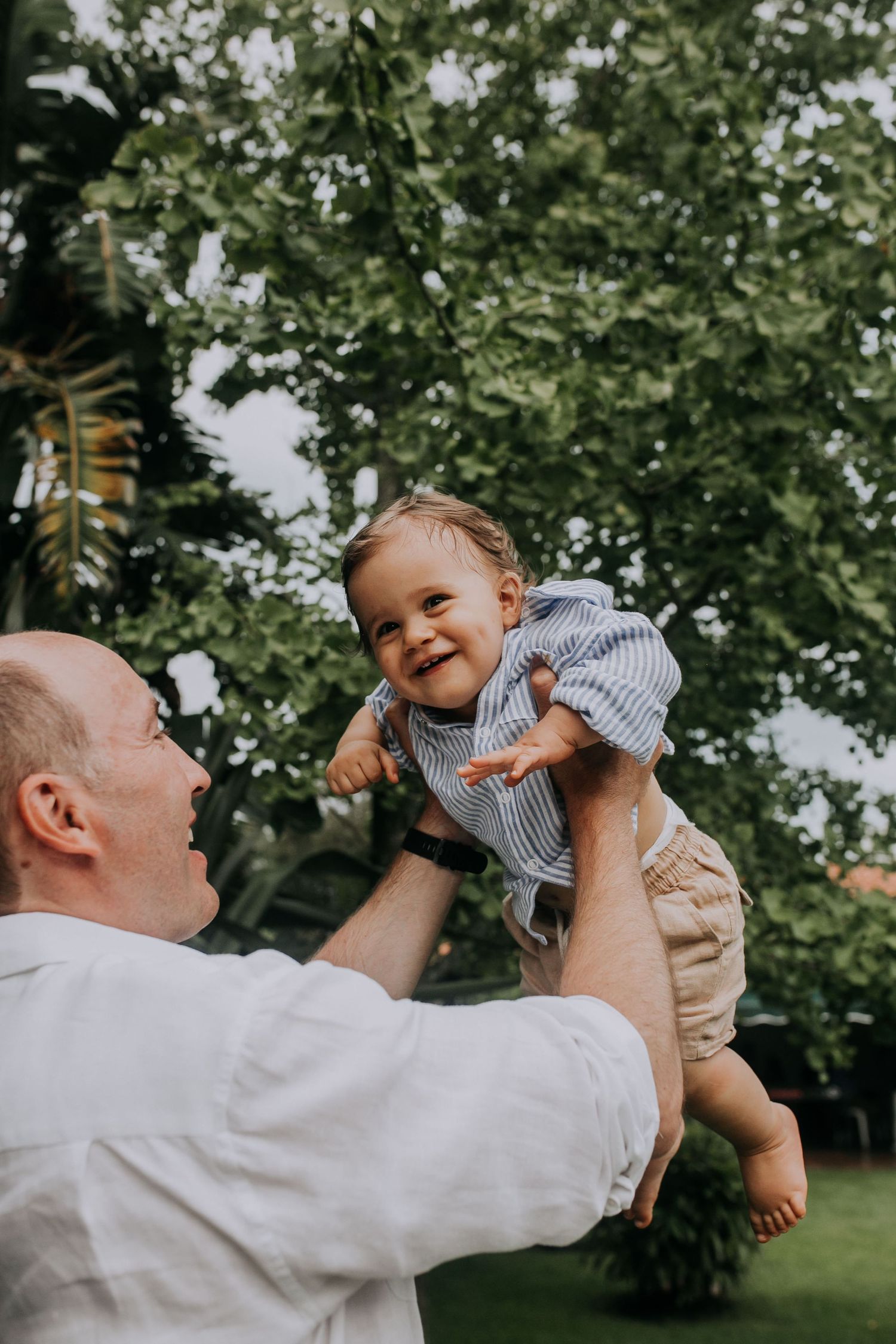 Joyful moment between adult and baby playing outdoors in summer garden setting.
