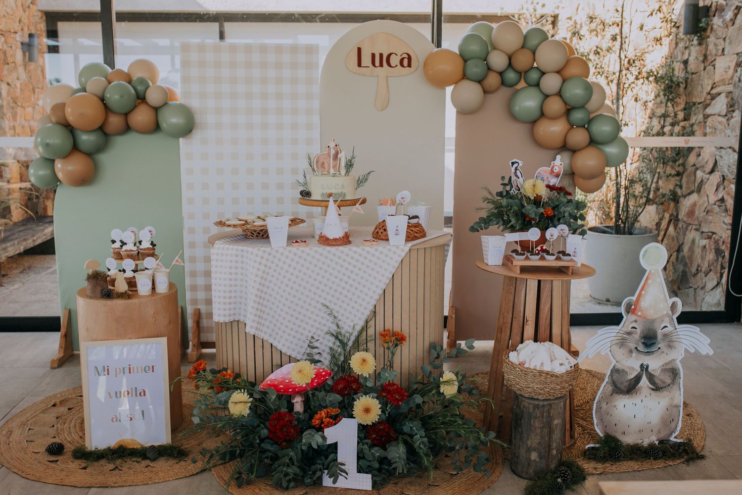 A rustic party setup with neutral balloon garlands, wooden crates, and a sign reading 'Luca' for a celebration.