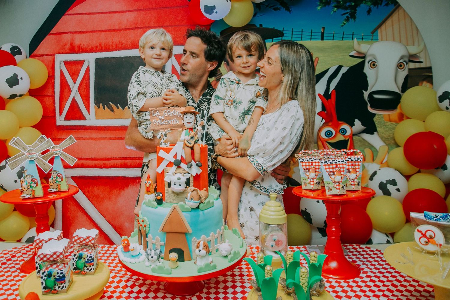A farm-themed party setup with red barn backdrop, balloons, and decorative cake display.