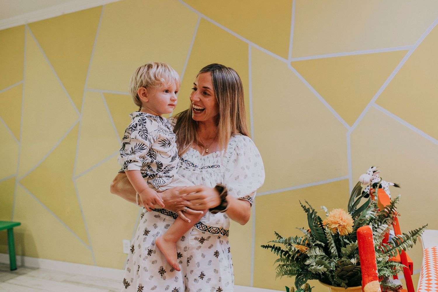 A festive scene with geometric yellow wall decor and decorative plants in the background.
