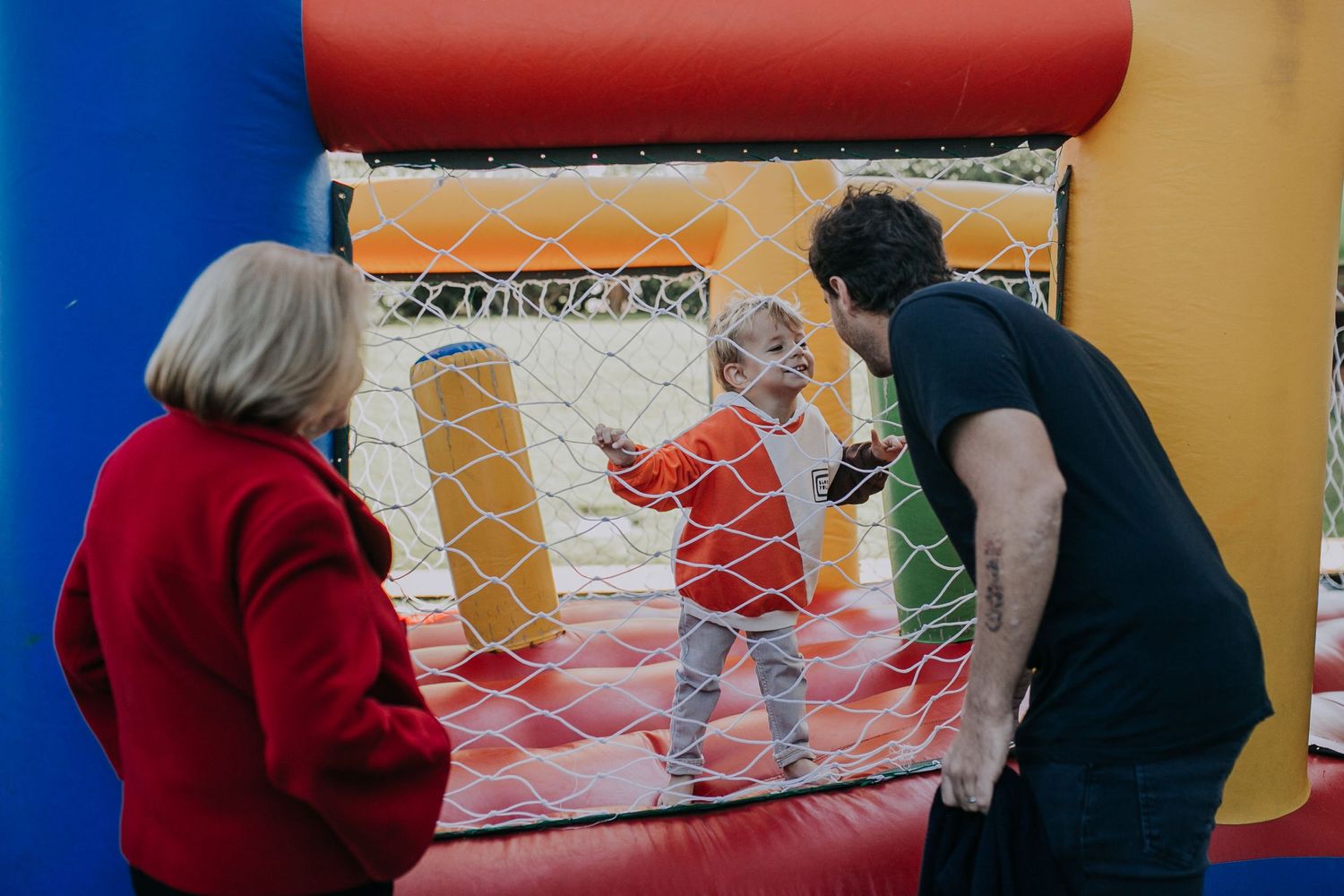 A child plays inside an inflatable bounce house while adults supervise.