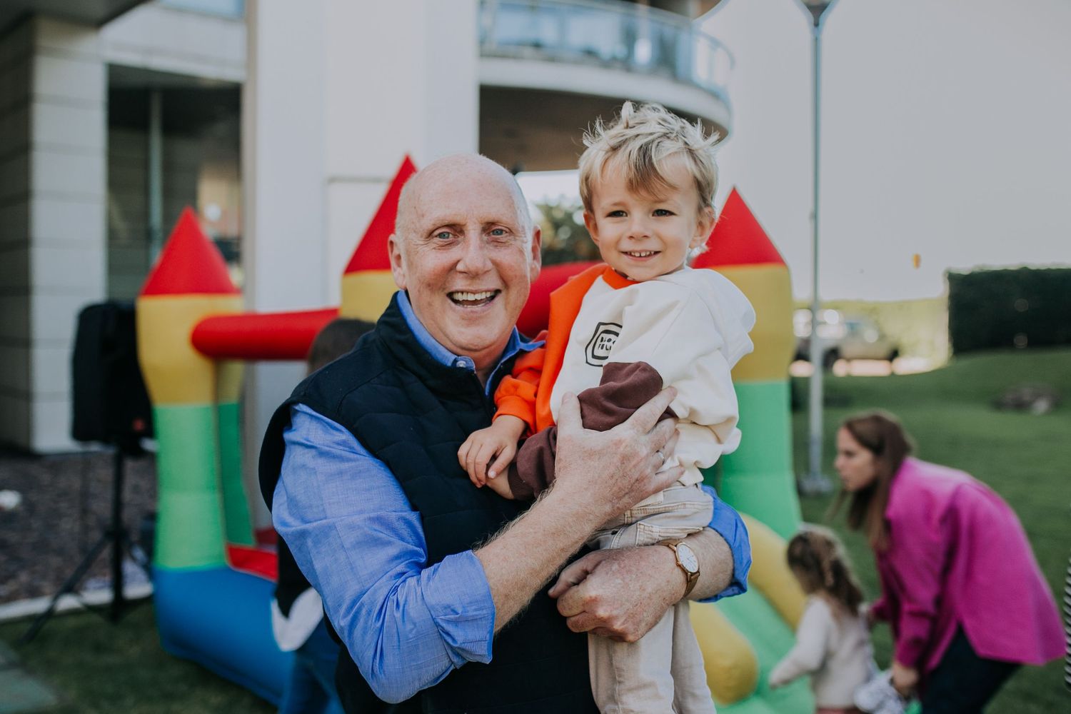 A joyful moment at an outdoor party with a bounce house in the background.
