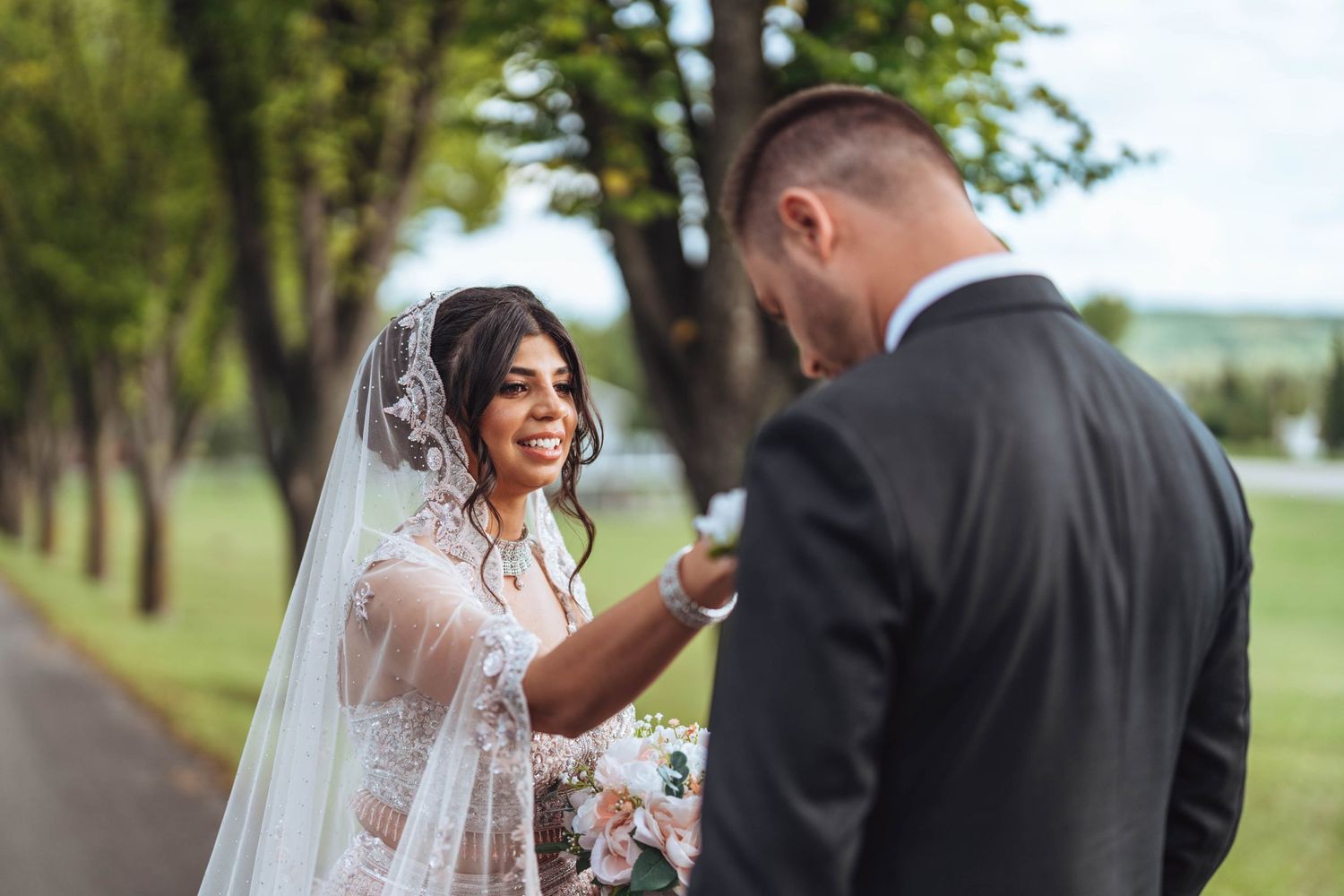 Bride adjusts groom's boutonniere. Wedding photography in the Calgary area.