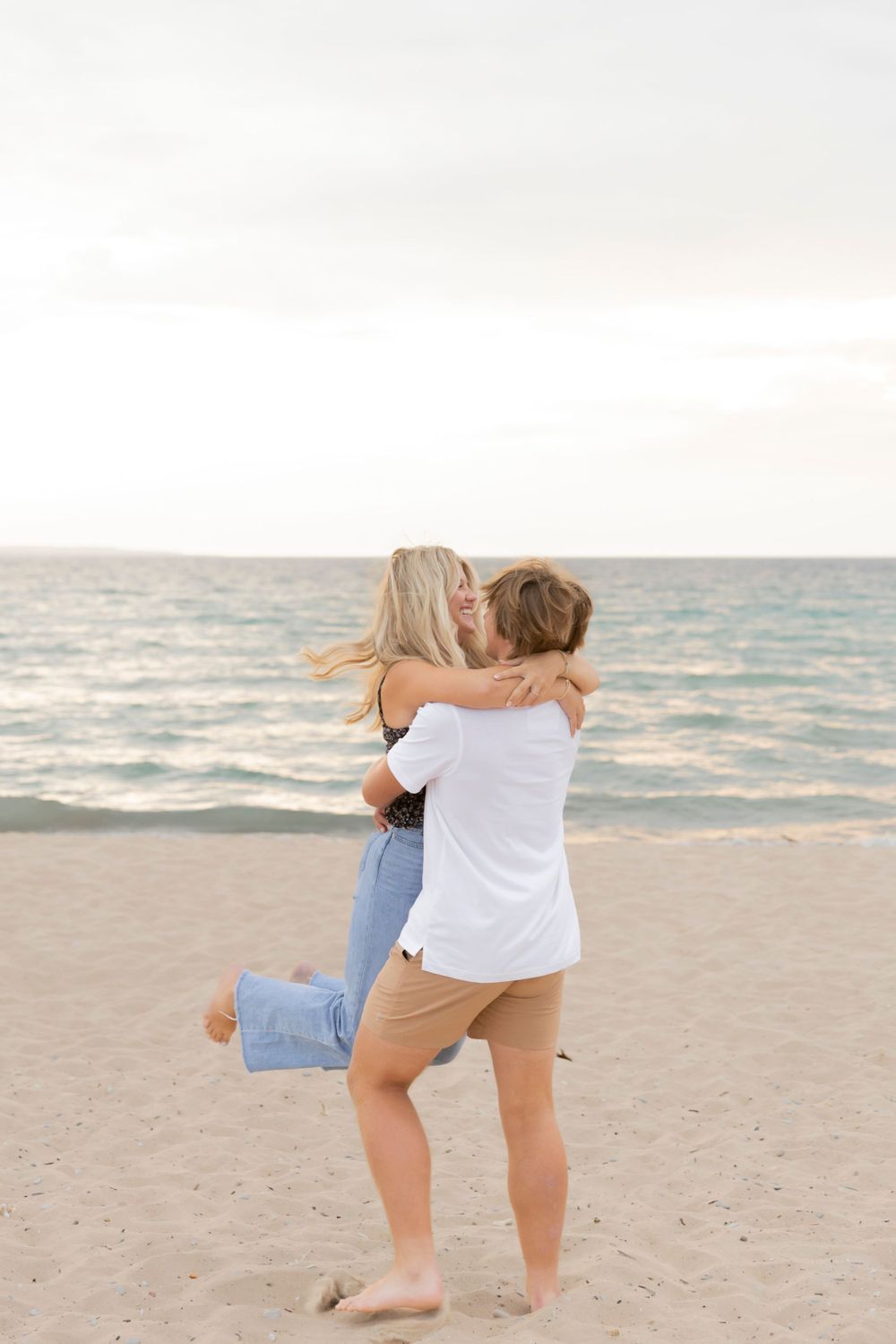 boy spinning his girlfriend on the beach in Michigan during a sunset