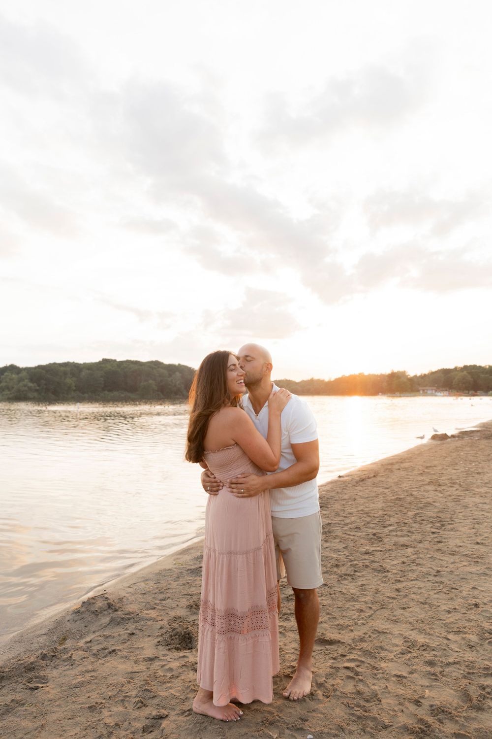 man kissing his wife on the beach at sunset in detroit michigan