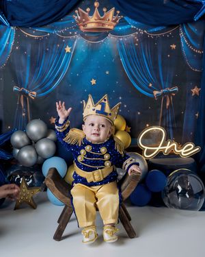 Royal-themed first birthday photoshoot setup with blue and gold colors featuring balloons and crown decorations.