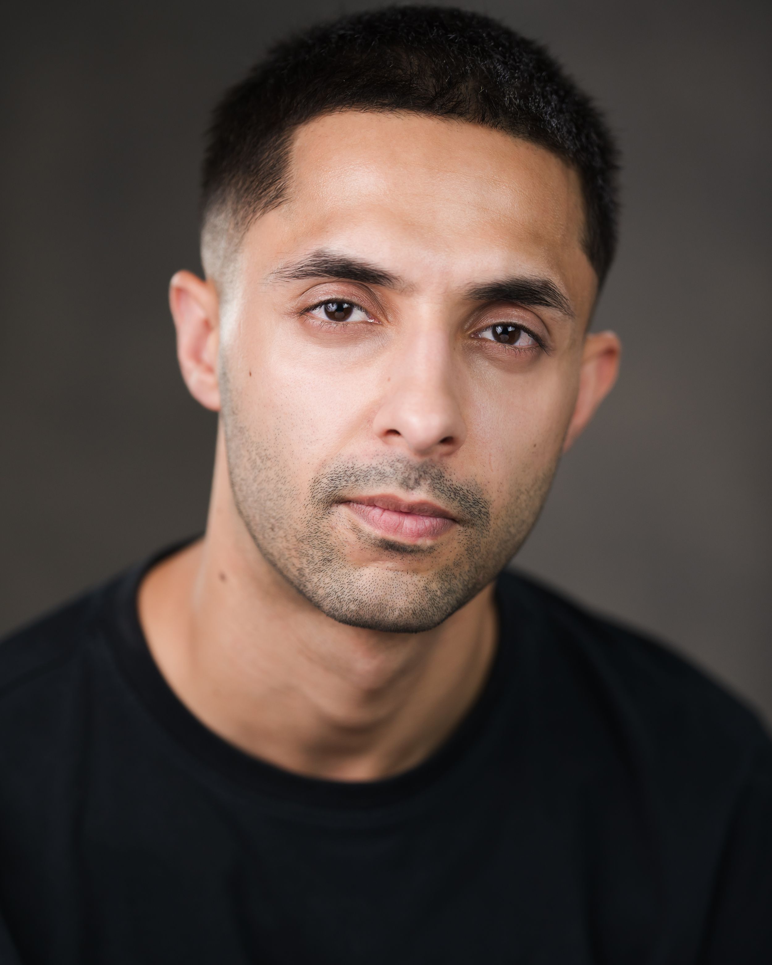 Professional headshot of person in black shirt against dark background. Headshots in Guildford, Surrey.