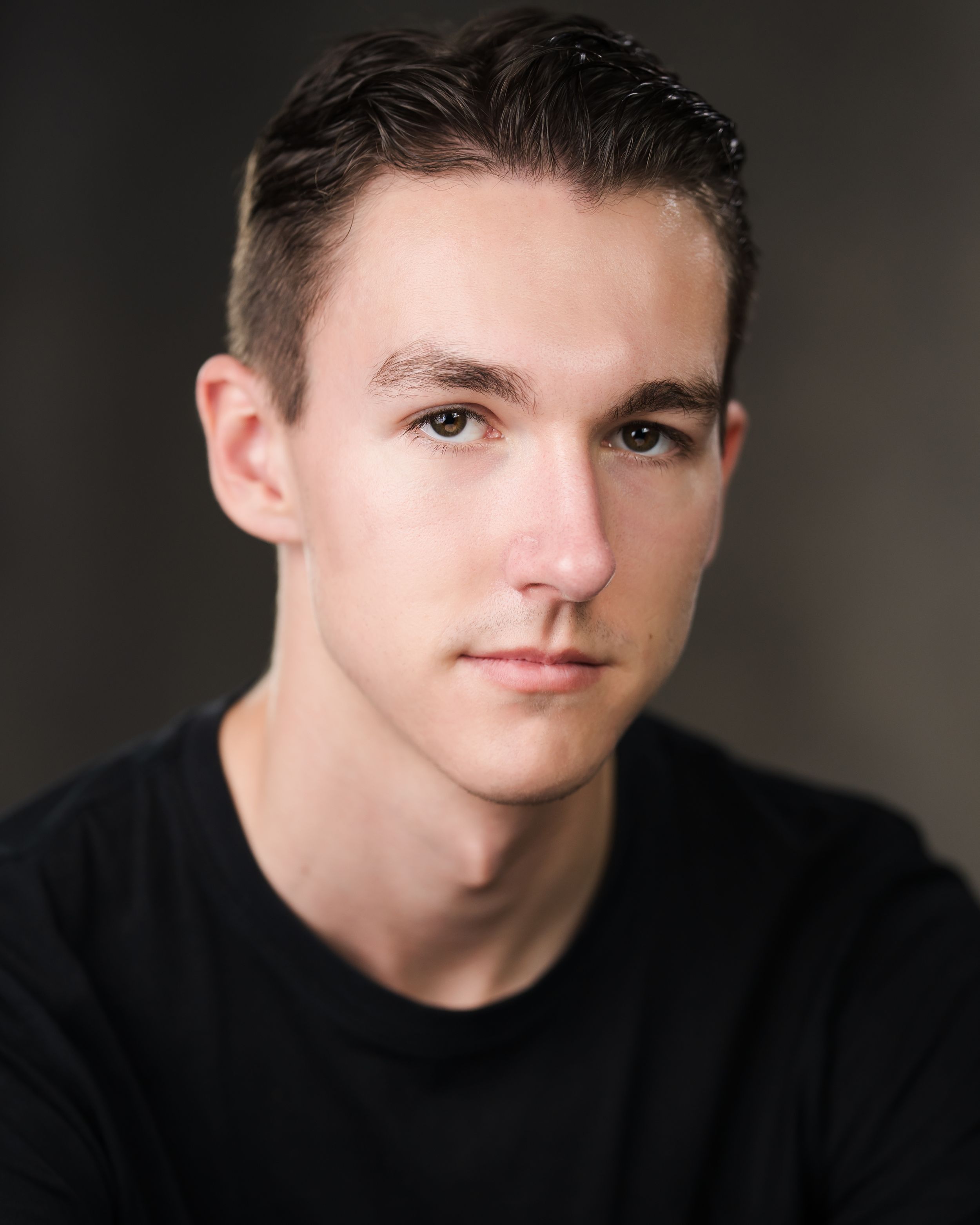 Professional headshot of person in black shirt against dark background. Headshots in Guildford, Surrey.