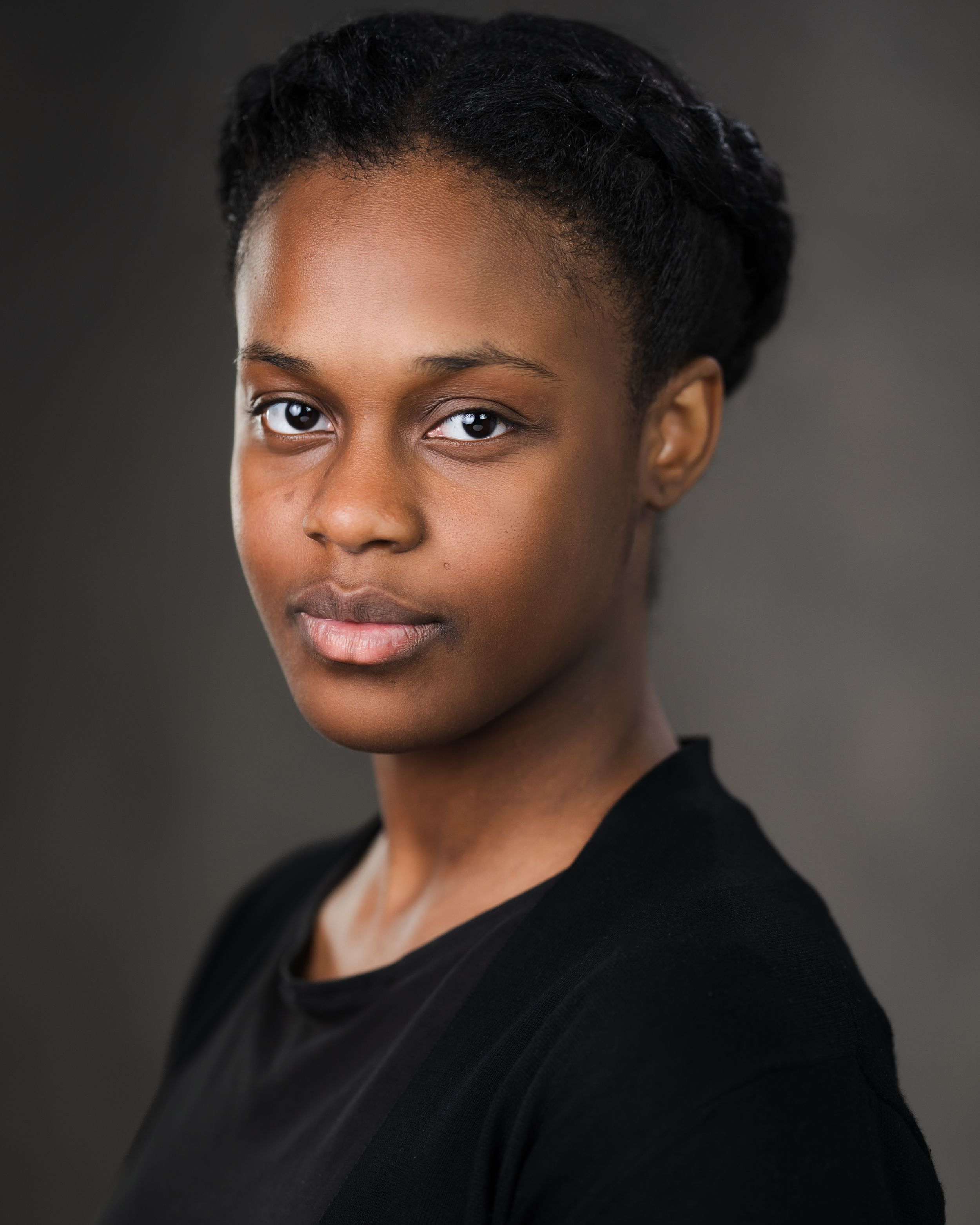 Professional portrait of person in black shirt with styled hair against dark background. Headshots in Guildford, Surrey.