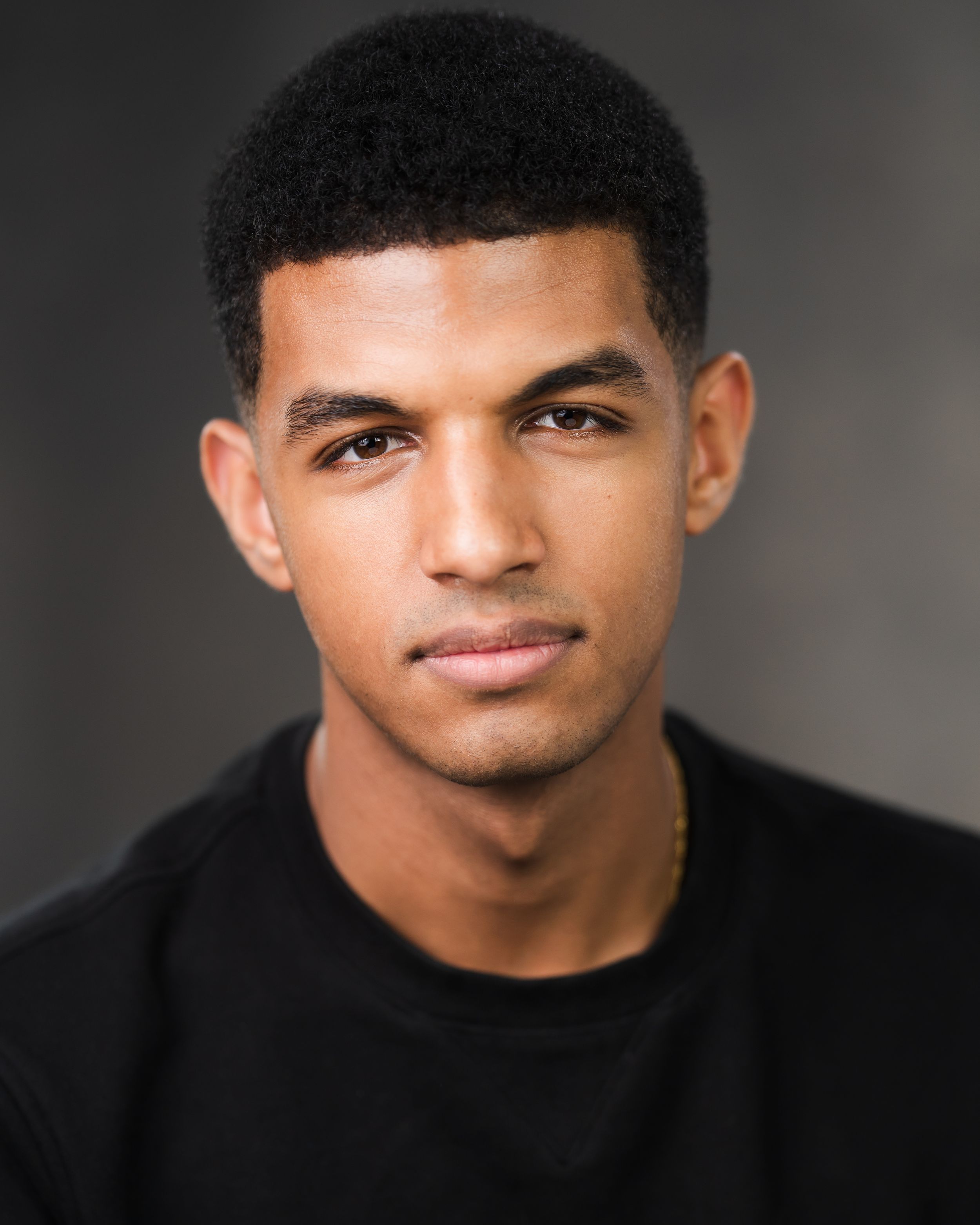Professional headshot of person in black shirt against dark background. Headshots in Guildford, Surrey.