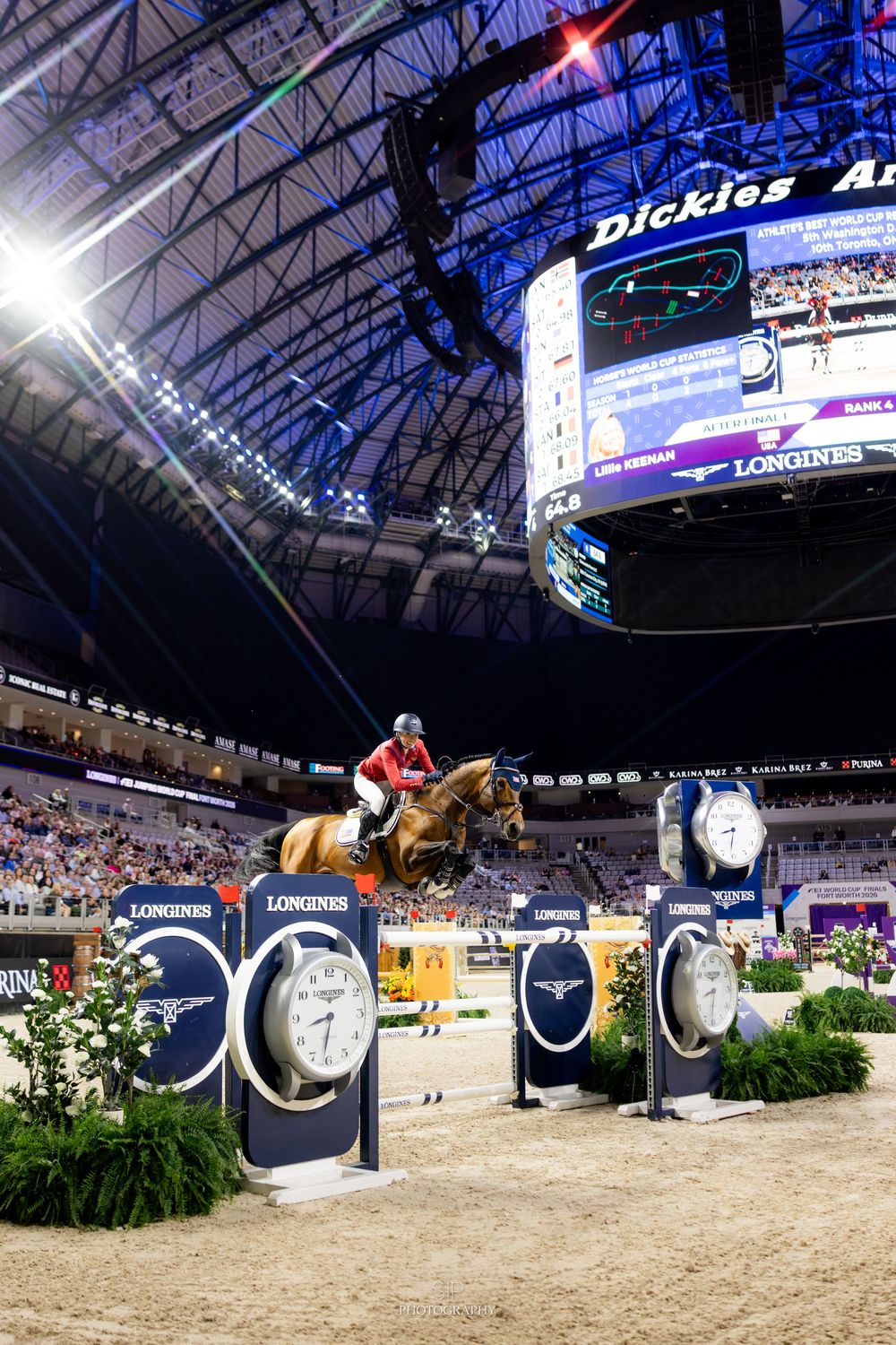 Show jumper leaping over obstacle at Longines indoor equestrian event inside Dickies Arena.