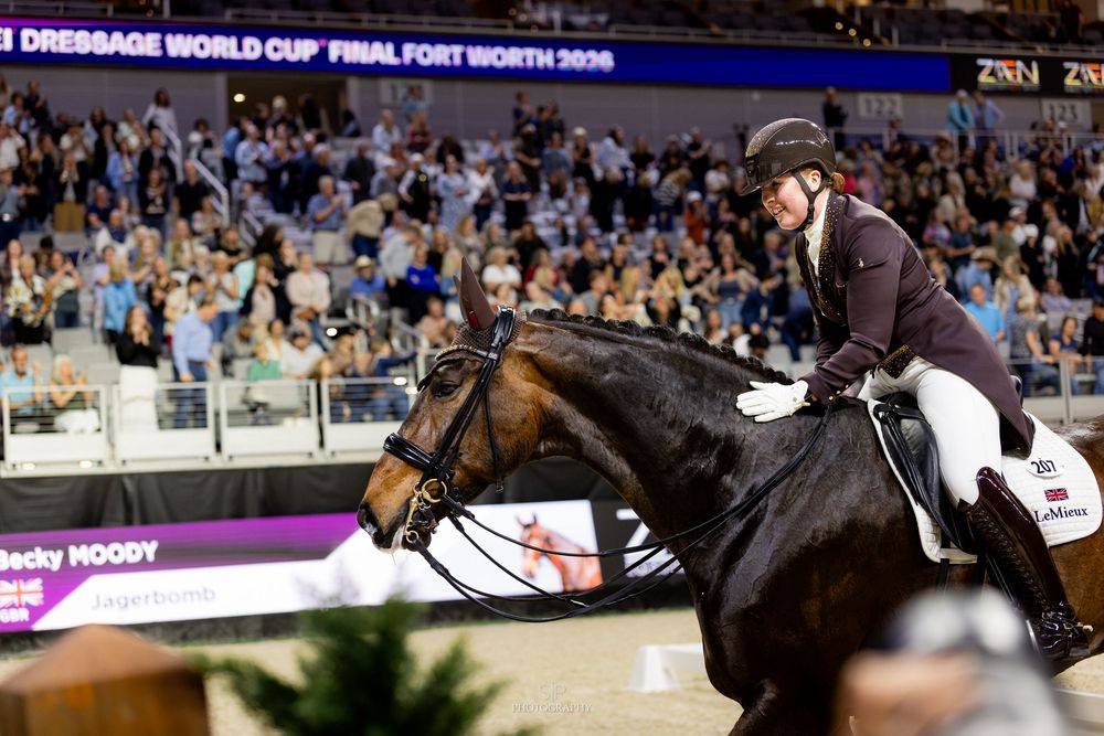 Rider on dark horse performs at FEI Dressage World Cup Final Fort Worth 2026 before packed arena crowd.