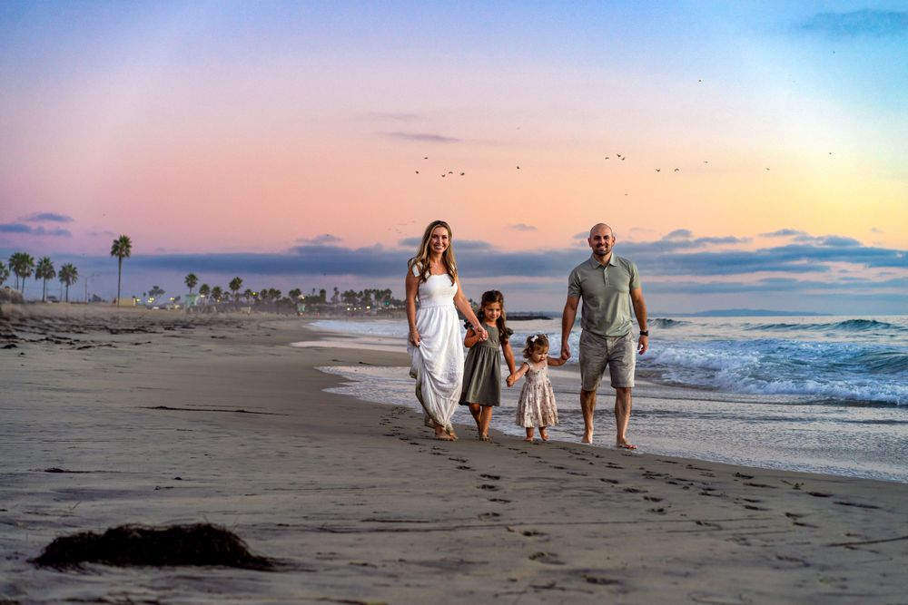 Peaceful beach scene at sunset with people walking along the shoreline.