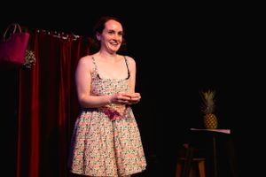 Stage performance with red curtain backdrop and pineapple prop. Theatre photography in Surrey.