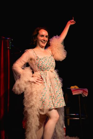A theatrical performance featuring a dancer in a vintage-style dress with flowing feather accessories. Theatre photography in Surrey.