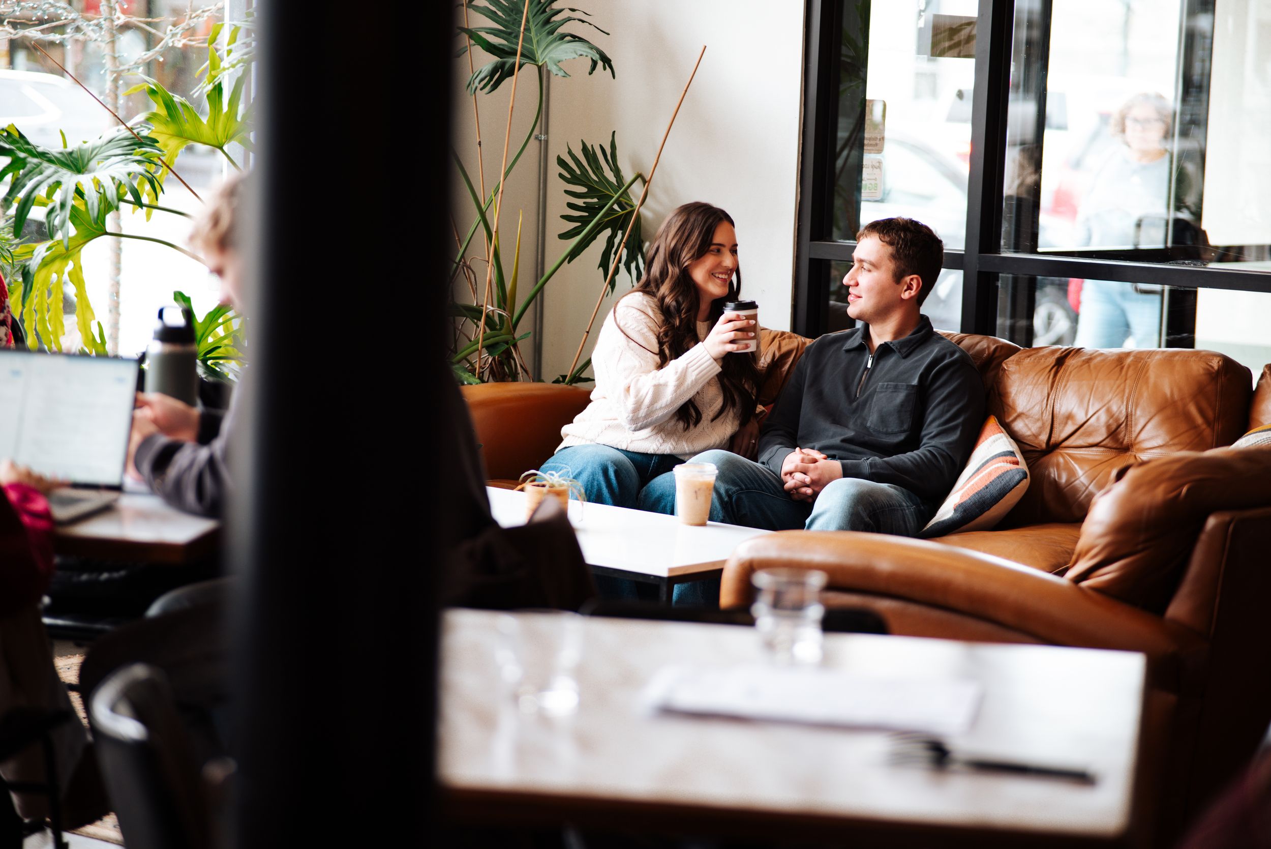 Two people having a business conversation in a modern cafe with leather seating and large windows in Bowling Green, Ohio.