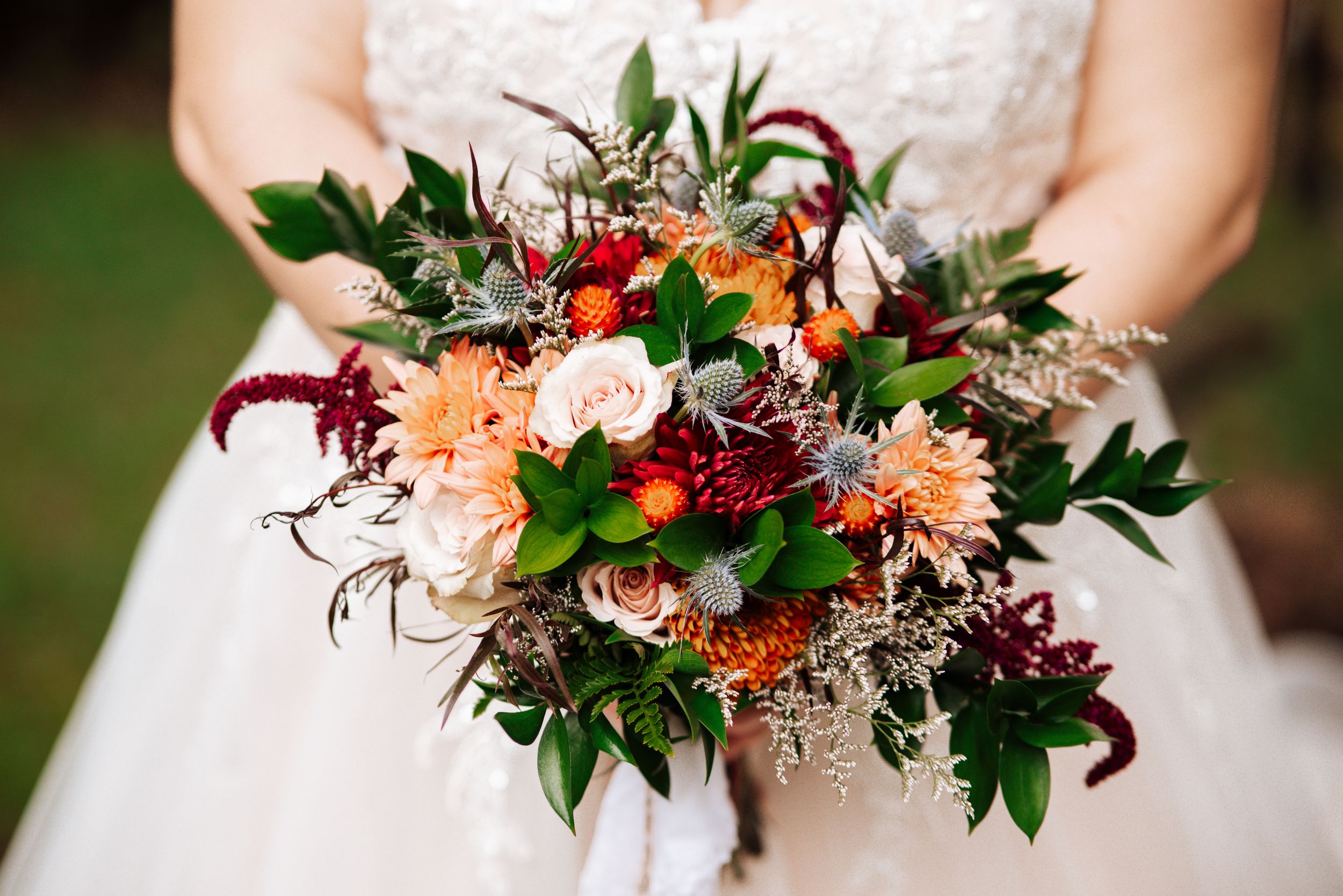 A collection of colorful wedding bouquets featuring burgundy, peach and white flowers with lush greenery.