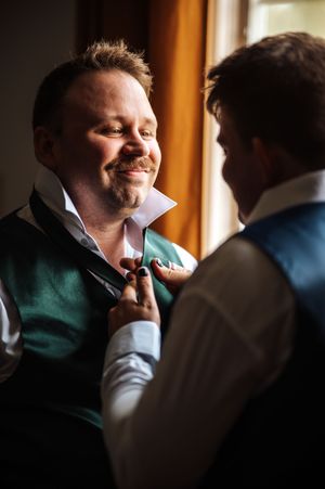 A sequence of candid moments showing someone in a green jacket adjusting their tie while being helped by another person.