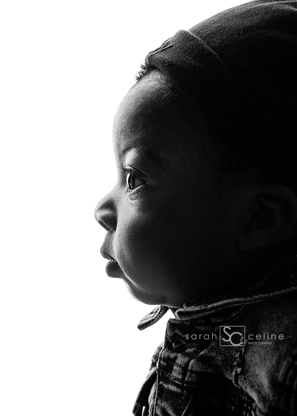 High contrast black and white profile portrait showing dramatic side lighting and deep shadows.