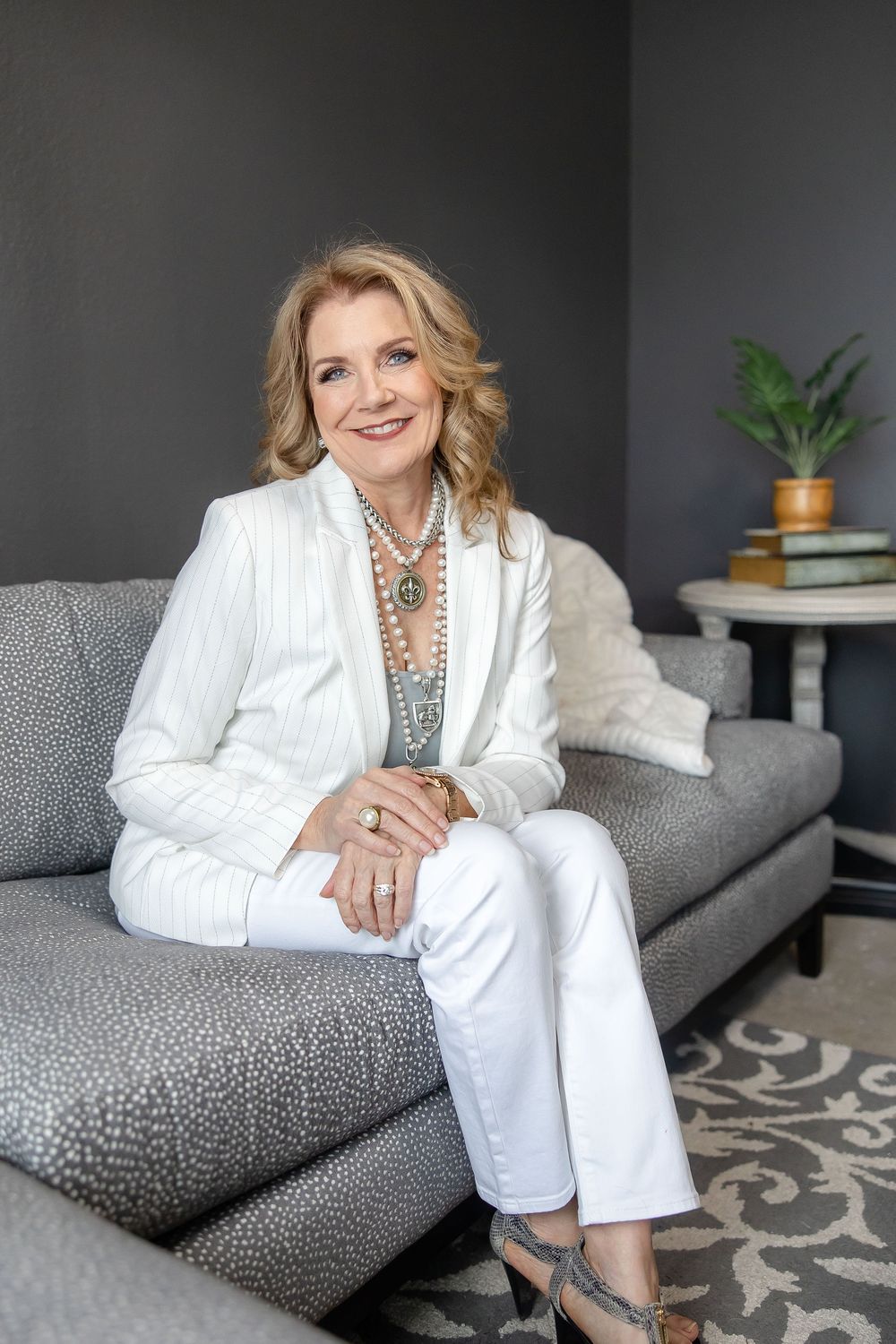 Professional portrait series showing elegant poses on a grey couch against dark wall with white blazer and animal print.