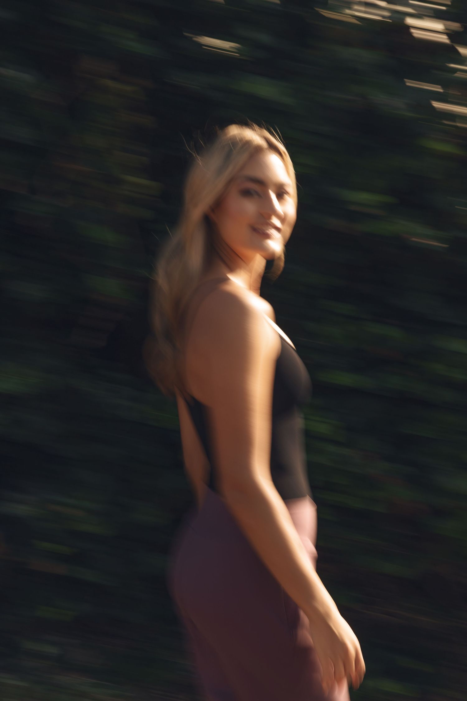 Motion blur creates an artistic effect of a person in workout attire moving against a dark background.