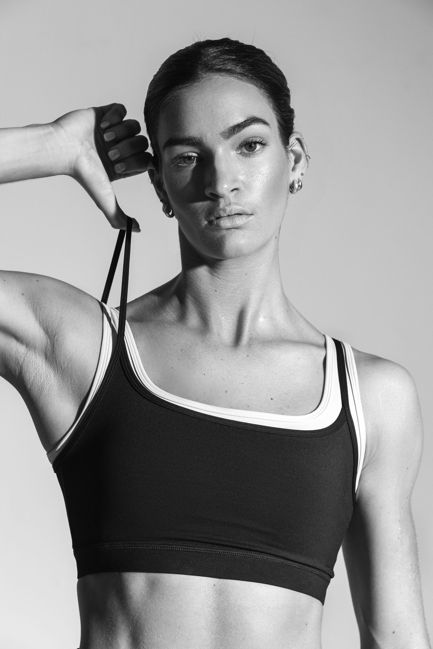 Black and white photo of a fit woman in a sports bra holding a jump rope, showcasing athletic physique.