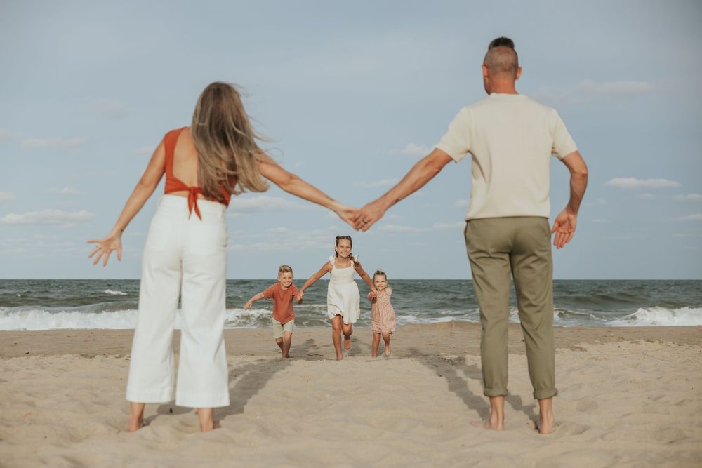 A sequence of photos showing a family holding hands and walking along a sandy beach at sunset.