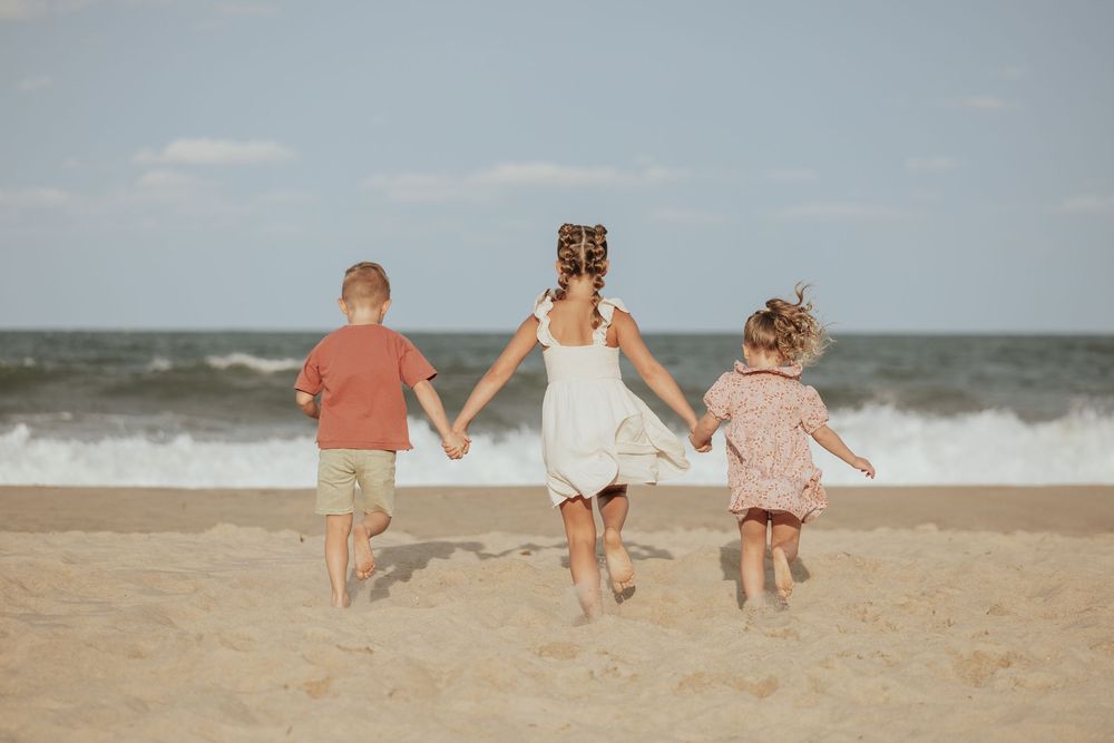 A progression of images showing people running joyfully along a sandy beach toward the ocean waves.