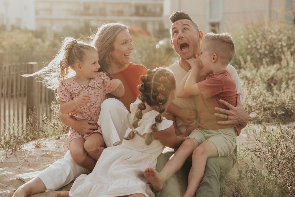 Family sharing laughter and playful moments during golden hour photo session in an outdoor garden setting.