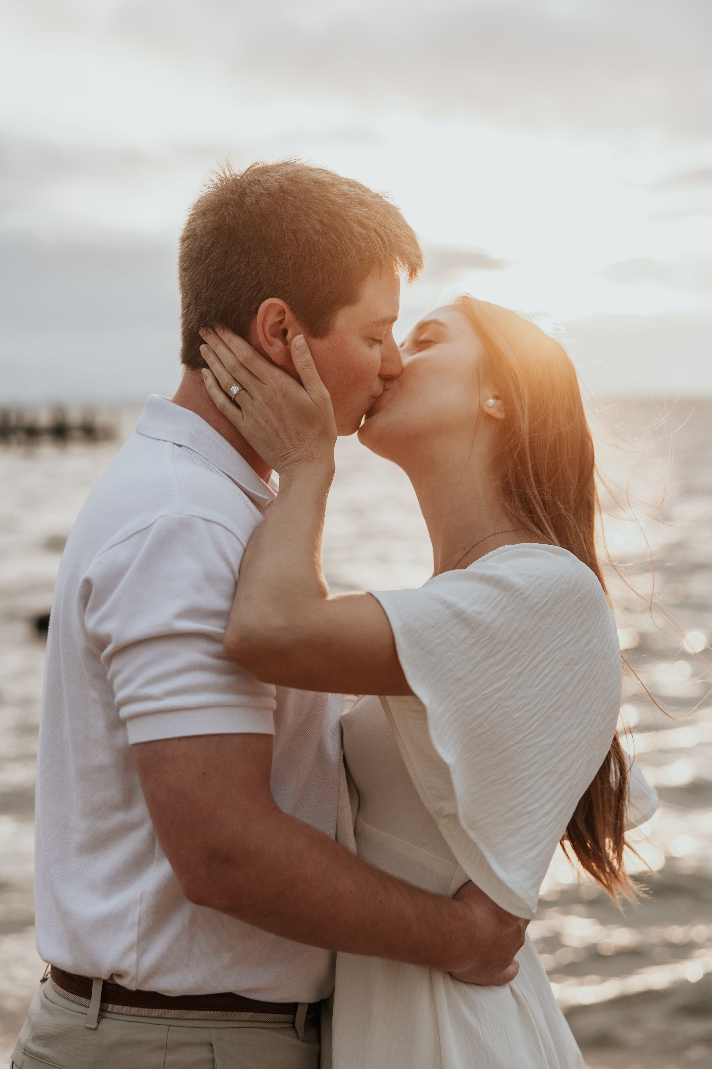 Romantic sunset beach engagement photo with golden hour lighting.