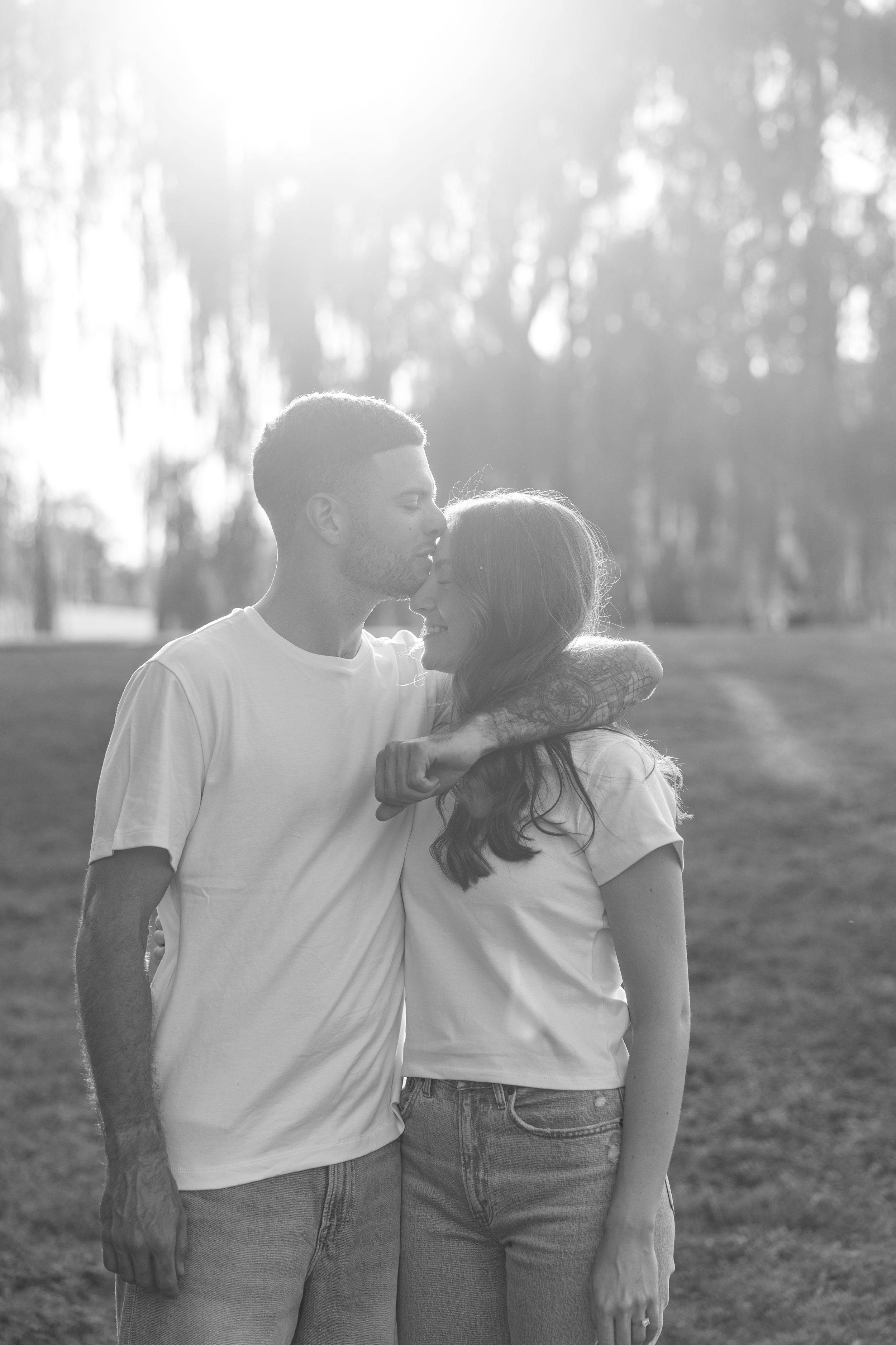 A tender black and white portrait of a couple sharing an intimate moment outdoors.